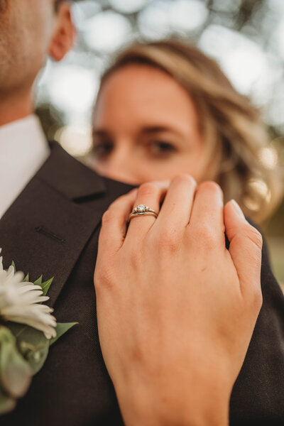 A bride looks into the camera and shows her ring while holding her groom in Charleston, West Virginia.