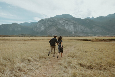 couple running toward mountain range