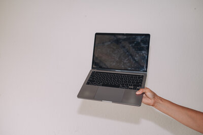 A woman uses a laptop with one hand while writing with the other