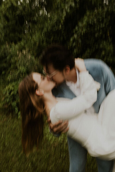 Motion blur photo with groom with glasses and a blue suit dipping bride