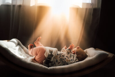 Newborn sitting below window in baby rocker