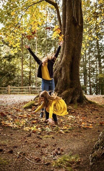 two girls in woods playing with leaves
