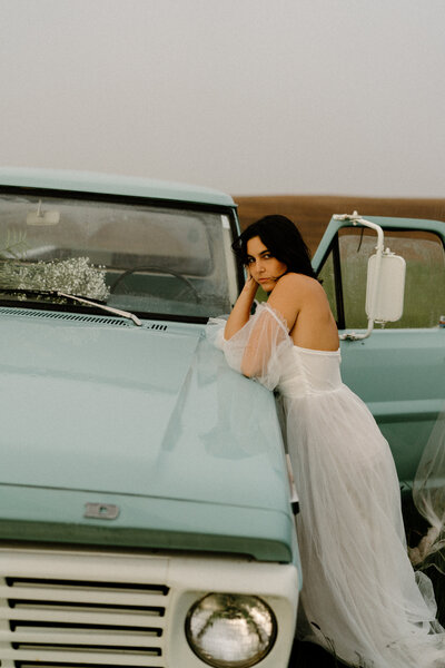 woman leaning against blue truck for her oregon portrait session