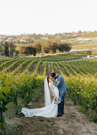 A newly married couple kissing in a Temecula, California vineyard.