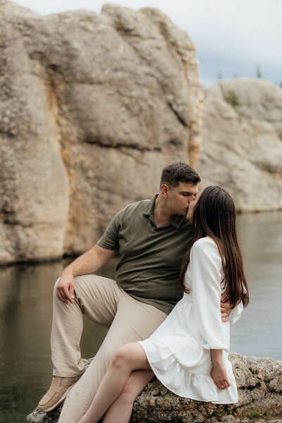 A couple kissing while stting on a rock in Sylvan Lake.