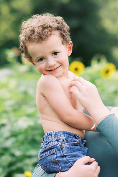 Little boy with jeans and no shirt being tickled by mom