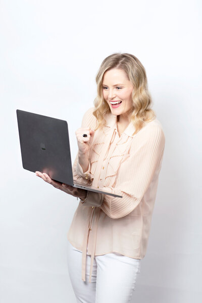 Photographer Alison McWhirter holding laptop and looking happy