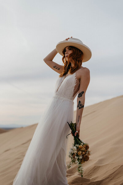 bride with hat and bouquet in sand