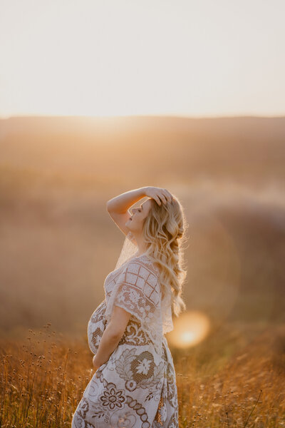 woman at sunset maternity photo with sunflare