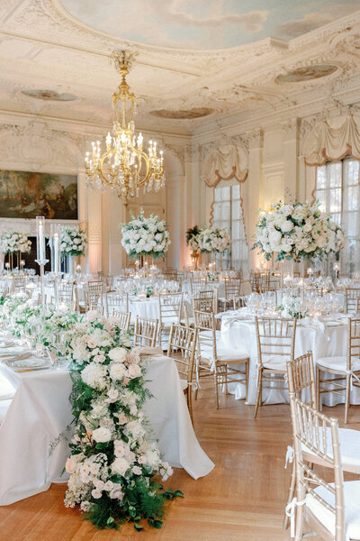 Newport mansion ballroom with tables set for wedding guests, adorned in flowers