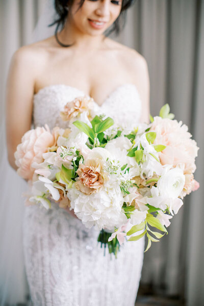 bride holding white and peach bouquet