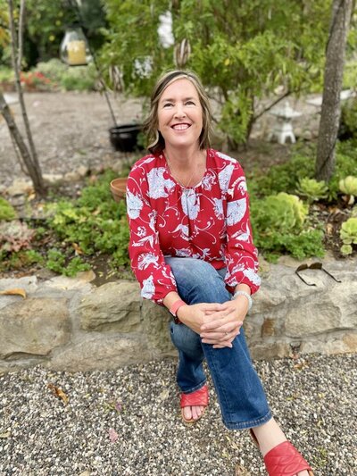 Woman smiling with legs crossed, symbolizing compassion, grounded support, and the healing presence behind Your Stellar Life