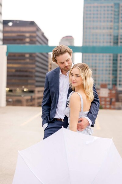 Woman's hand rests on fiancee's shoulder as they stand in Lake Minnetonka.