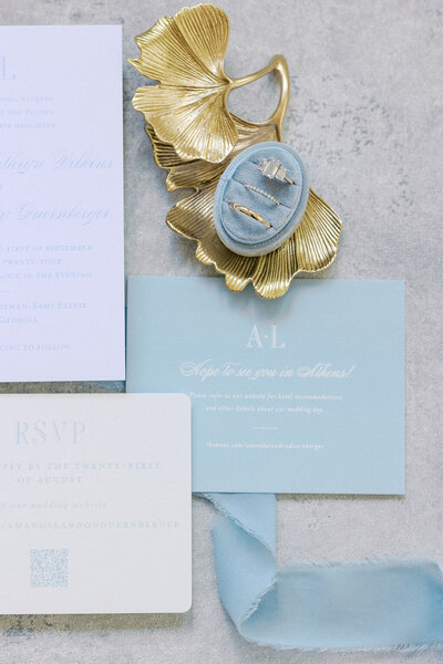 Blue and white wedding invite details with gold ginko earrings