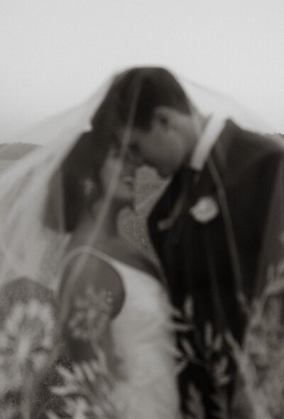 Bride and groom laughing under bridal veil