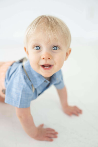 beautiful blue eyed one year old boy crawling around in an oklahoma city photography studio