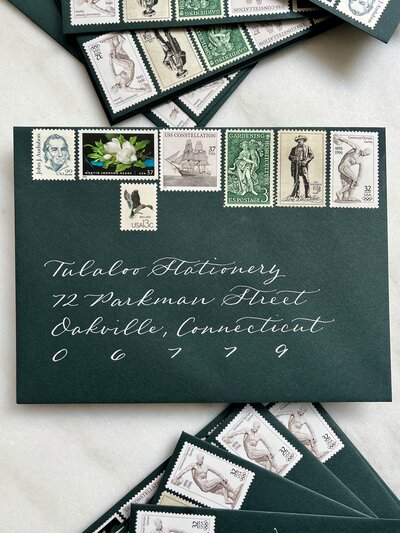 Dark green wedding invitation envelopes with white ink calligraphy and vintage postage