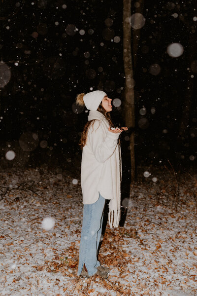 woman standing outside smiling while it snows