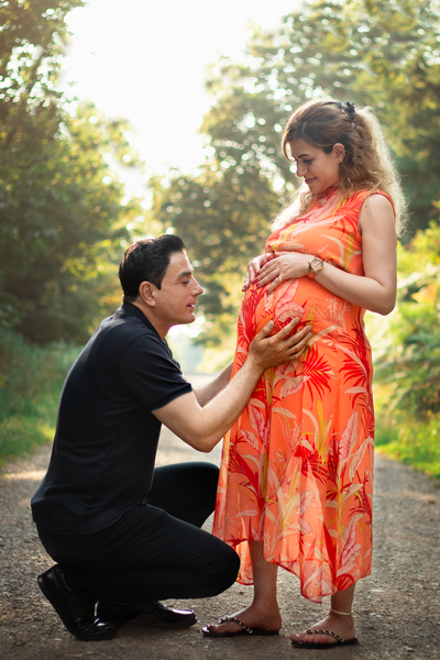 Husband kneels to hold his pregnant wife's belly