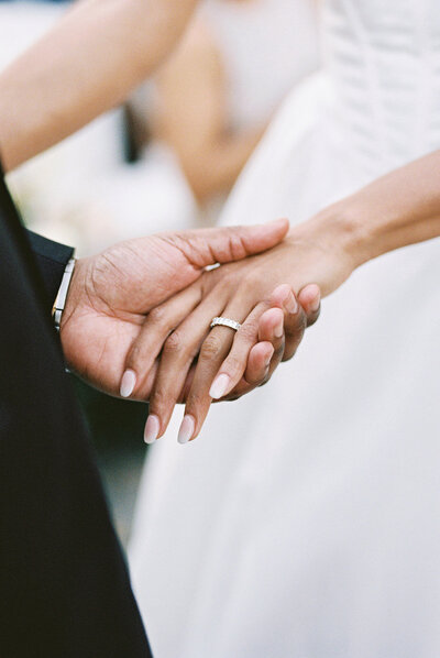 Close-up of bride and groom holding hands during their wedding ceremony in Altos de Chavón, photographed by Asia Pimentel.