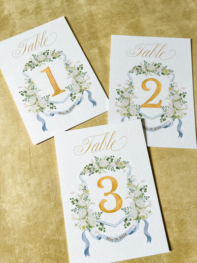 A set of 15 wedding table number cards featuring the client's wedding crest by Alicia Betz of The Welcoming District.