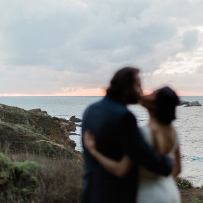 Couple embracing in a kiss with the Big Sur sunset in the background