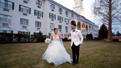 A formal bride and groom walk hand in hand.