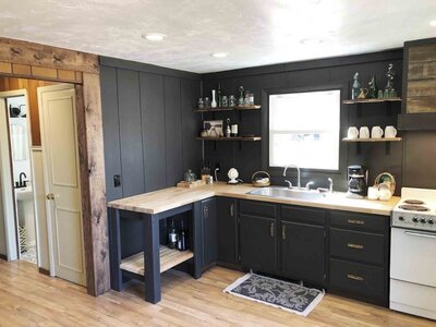 renovated kitchen with black cabinets and butcher block counter top