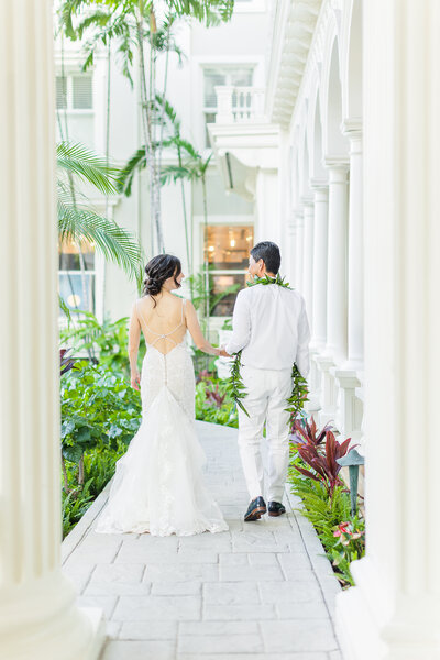 a couple walking down the pathway at moana surfrider in waikiki