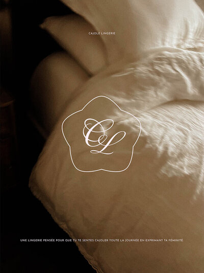 Maquette de présentation de l'identité visuelle de cajole lingerie, qui représente l'ambiance confortable des grasses matinées. L'image montre un lit avec une literie en lin et le logo icône de la marque et son slogan.