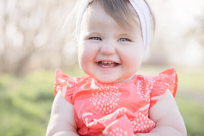A toddler girl smiling at for a portrait