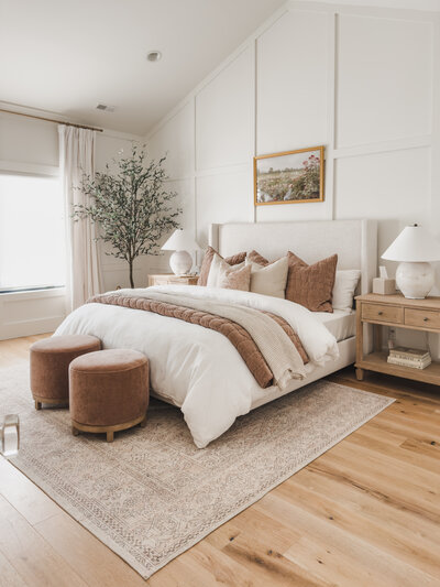 The primary bedroom at Woodlawn House features a vaulted ceiling and custom millwork in an elegant white