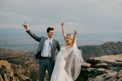 Couple cheering on top of a mountain in celebration of their elopement