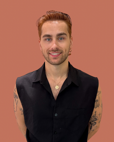 Ruby, female hairstylist with balayage hair, dressed in a black tee, exuding professionalism.