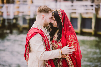 white and indian bride and groom touch foreheads at the docks of chateau la mer before their fusion wedding