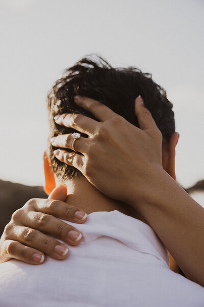 brides hands on back of grooms head with wedding ring