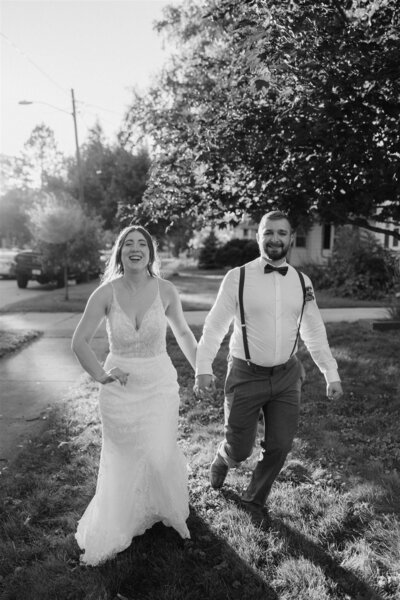 bride and groom running to camera holding hands and smiling