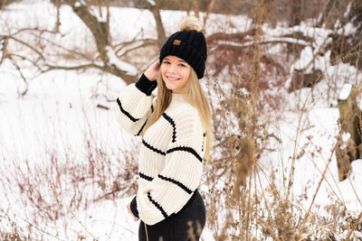 High school girl poses for her senior pictures in the snow.
