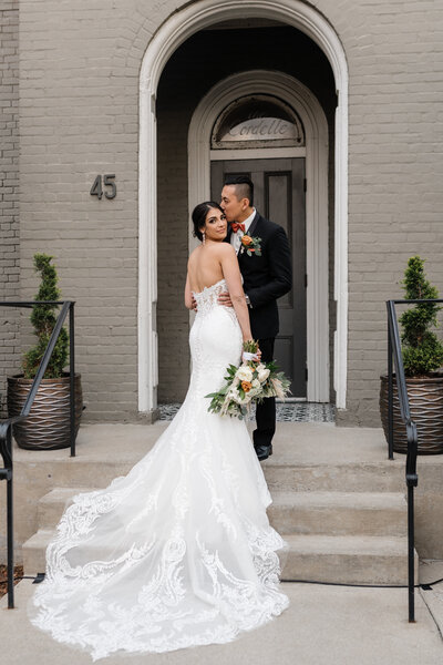 groom kissing bride on the cheek in on steps