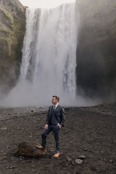 Groom standing in front of Skógafoss waterfall in Iceland