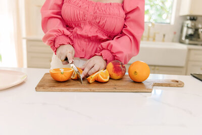 Mollie Mason's hands slicing oranges on a cutting board at her counter