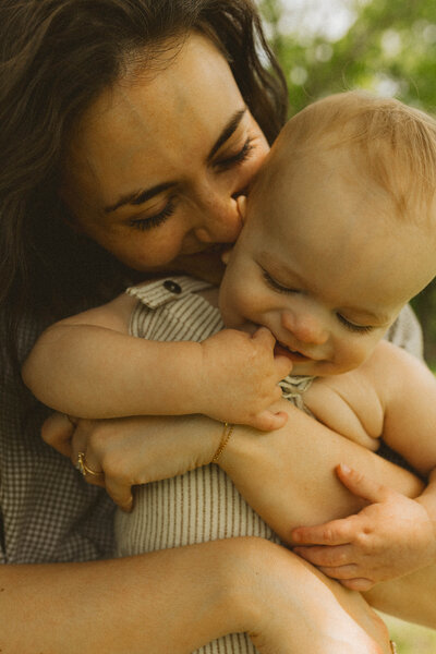Close-up of mom snuggling and holding 1 year old son and kissing cheecks