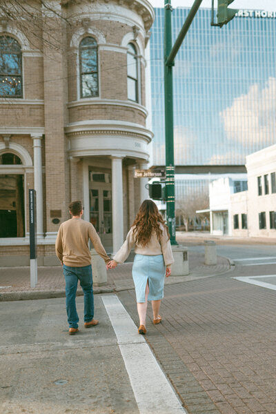 A couple holding hands walking across the street in downtown Lafayette, Louisiana. 