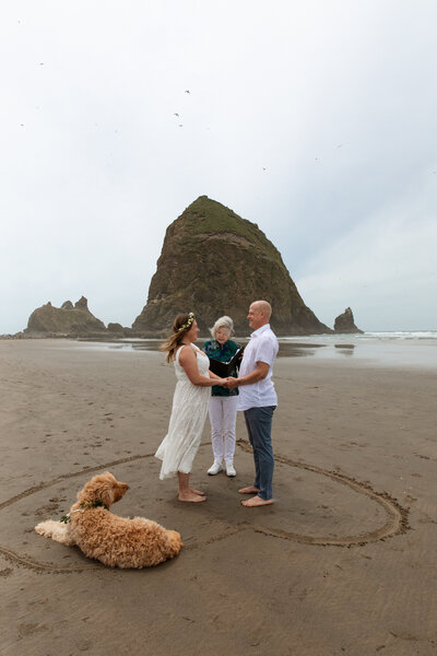 A couple holds hands during their intimate wedding ceremony in Canon Beach, Oregon. 