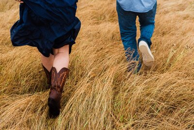 A girl through a field of golden grass in cowboy boots