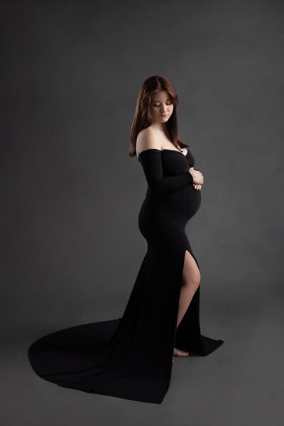 pregnant woman cradling her belly wearing a black dress