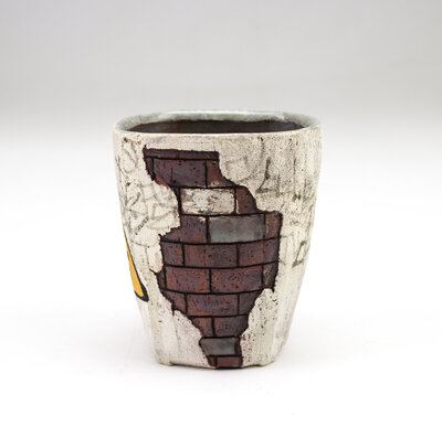 A ceramic cup that resembles plaster falling apart from red bricks with painted cacti and graffiti