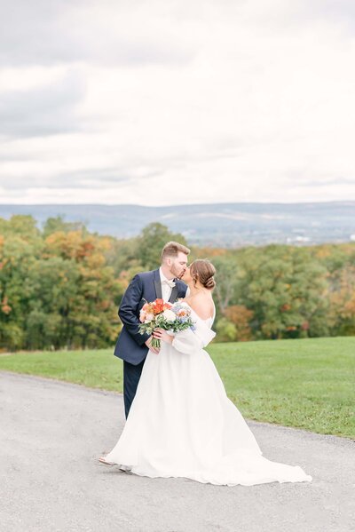 couple under the veil black tuxedo and white flowers for btide