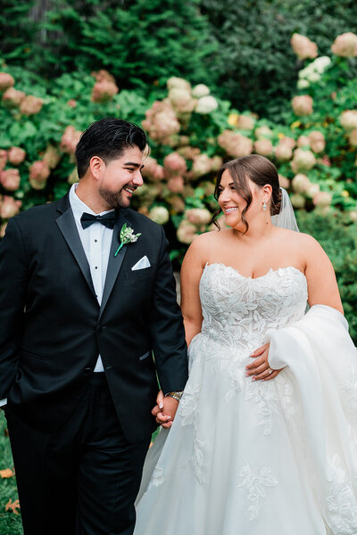 A married couple holding hands and smiling at one another