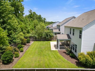 Spacious backyard in Leland with green lawn, screened patio area, and wooded area for privacy